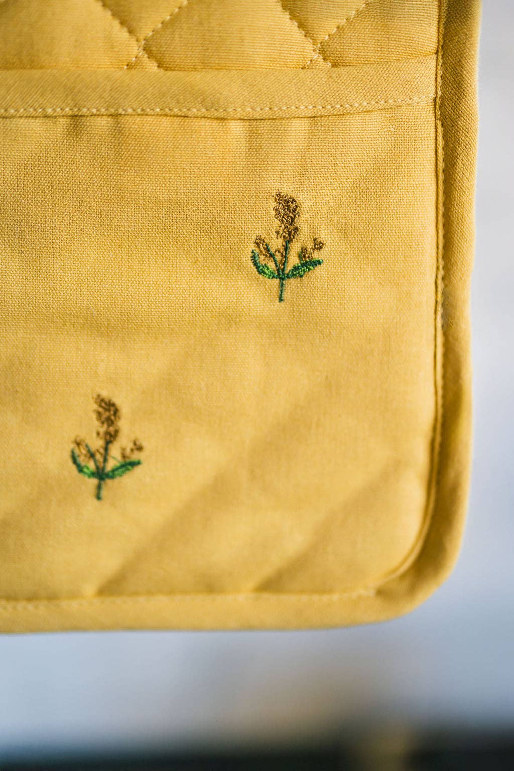 Yellow fabric with embroidered green floral patterns on a white background