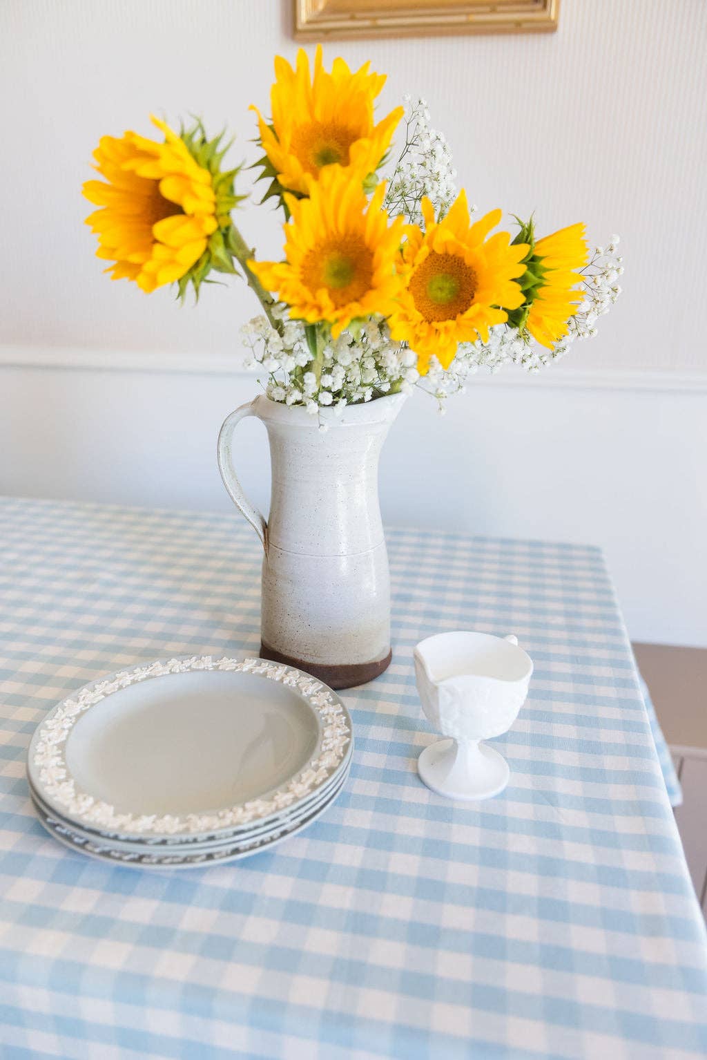 Vase of sunflowers on a table with blue gingham tablecloth