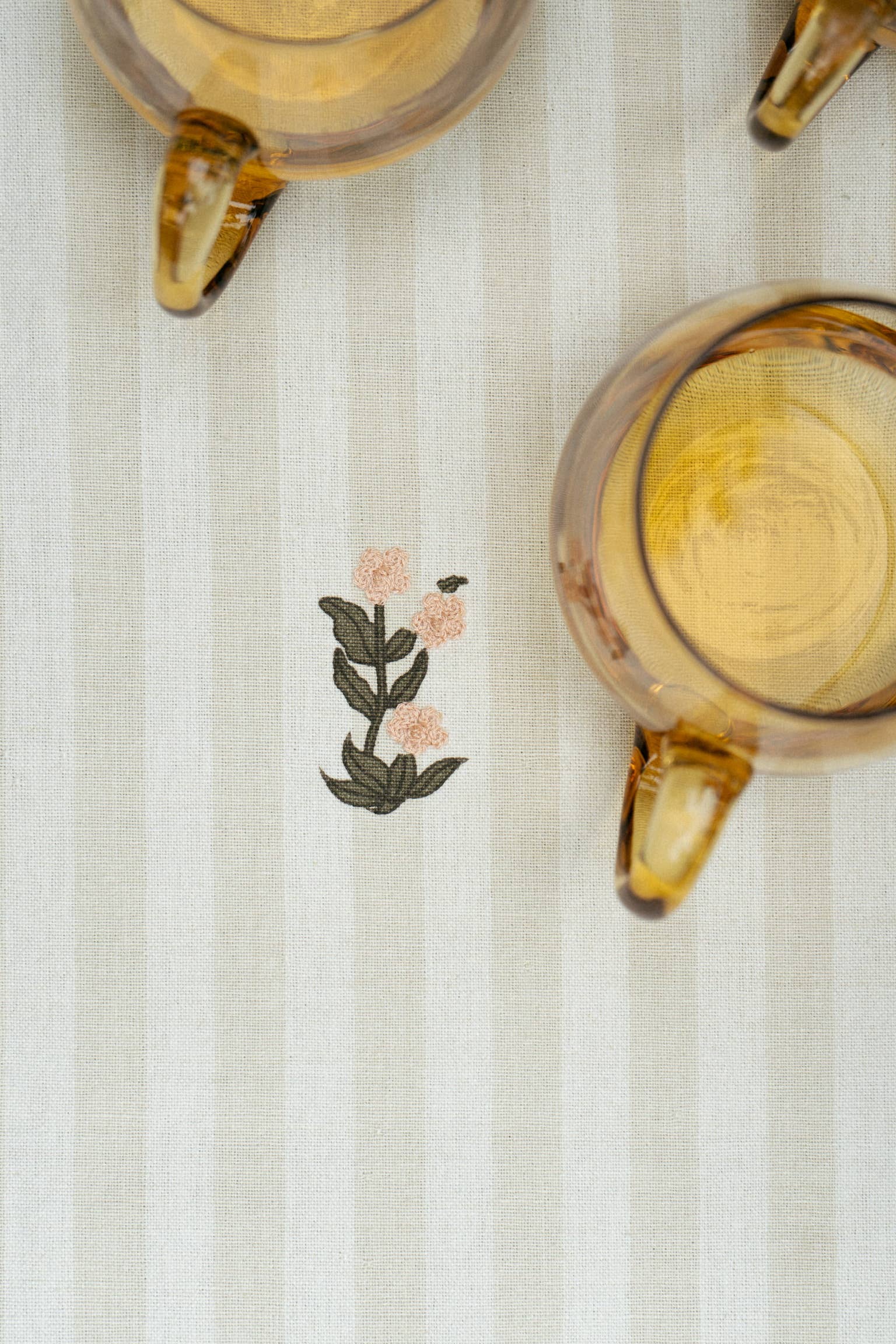 Two glass mugs with floral design on a white textured surface