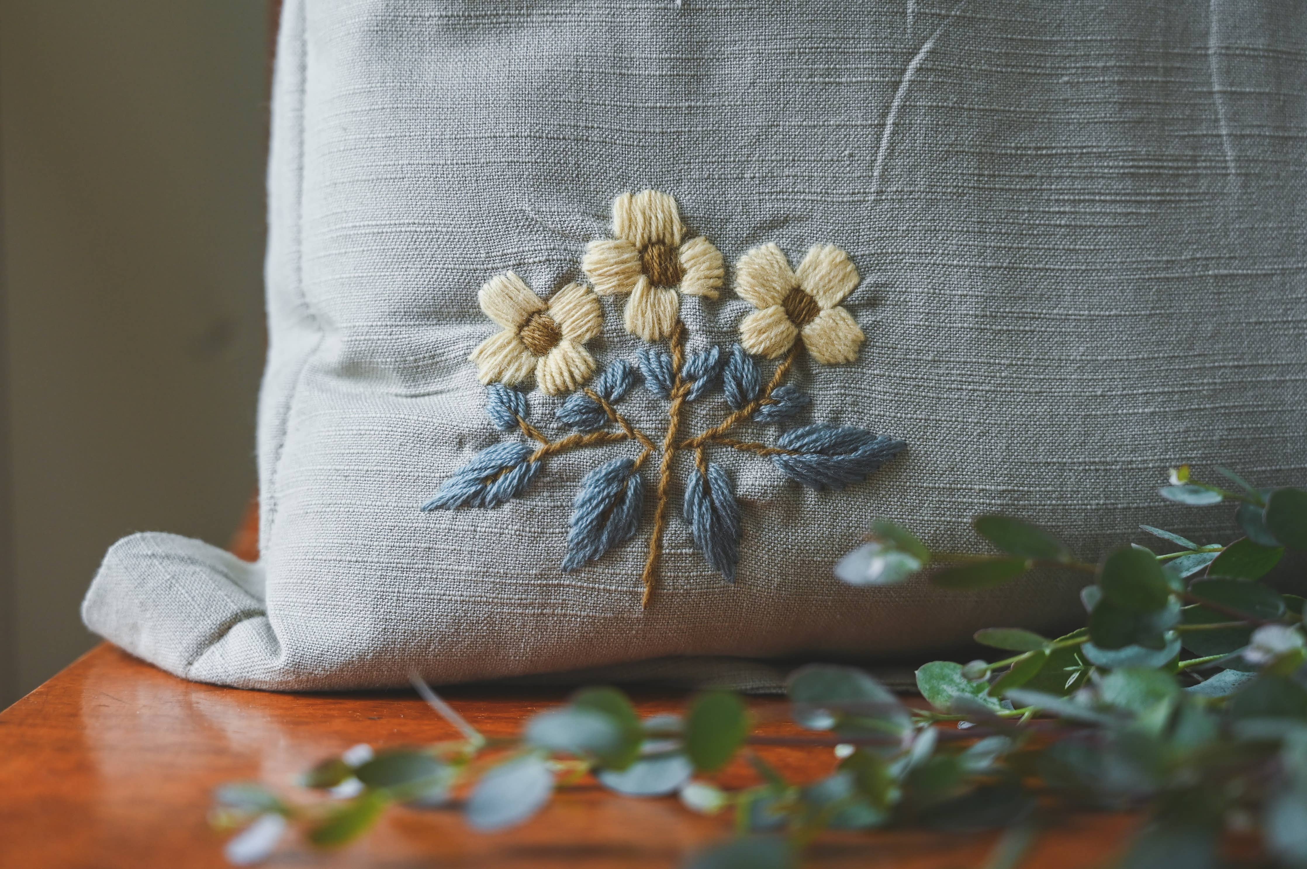 Textured floral pillow with hand-sewn wool embroidery detail