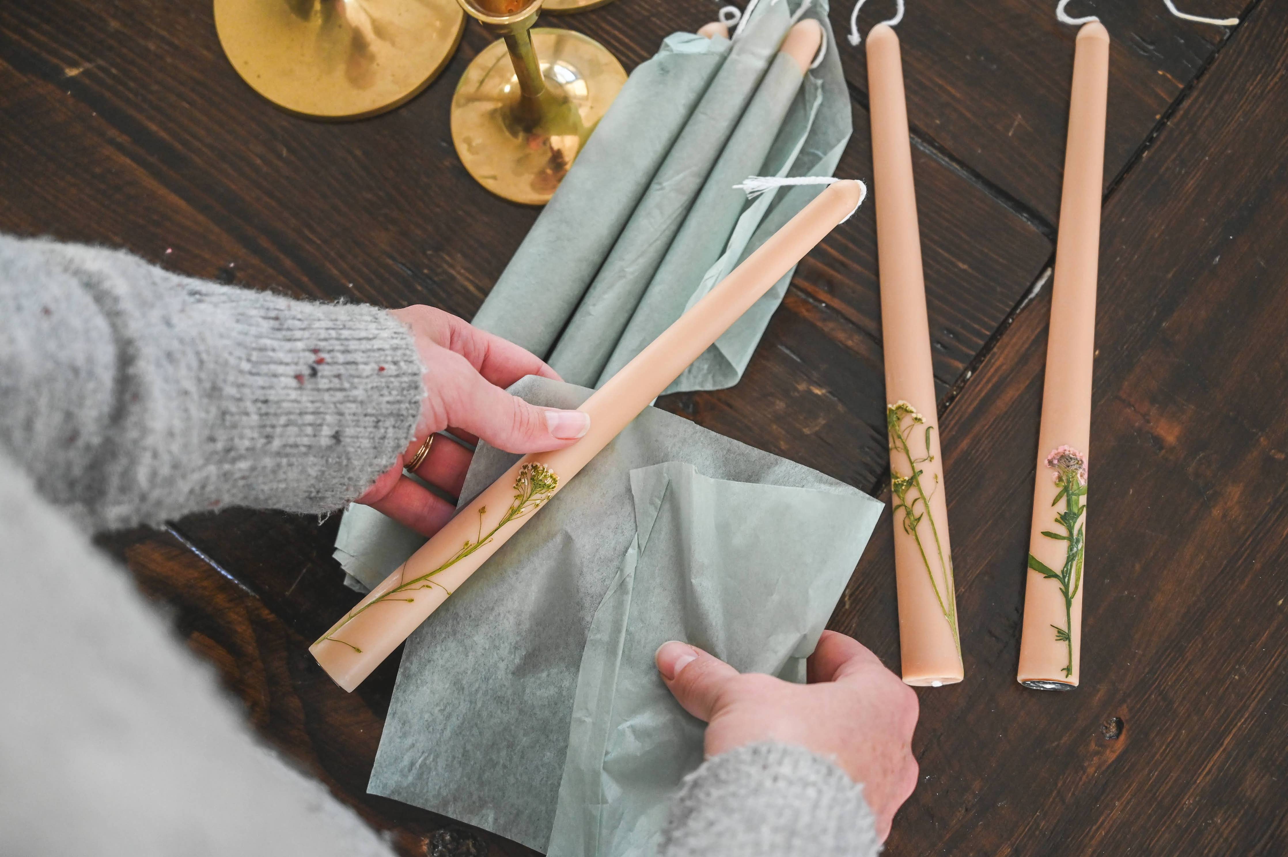 Person handling decorative candles on a wooden surface