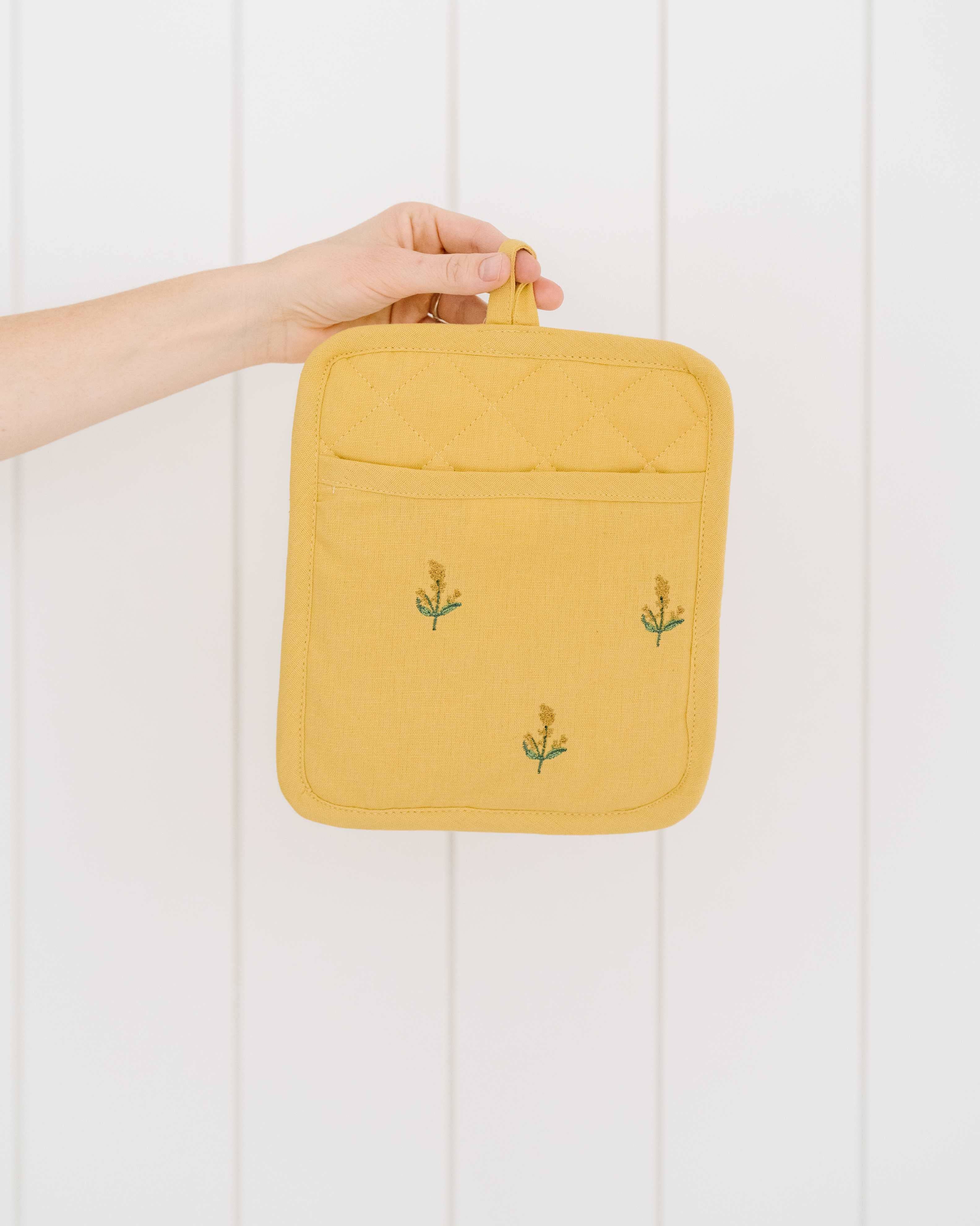 Embroidered pot holder in soft yellow with hanging loop