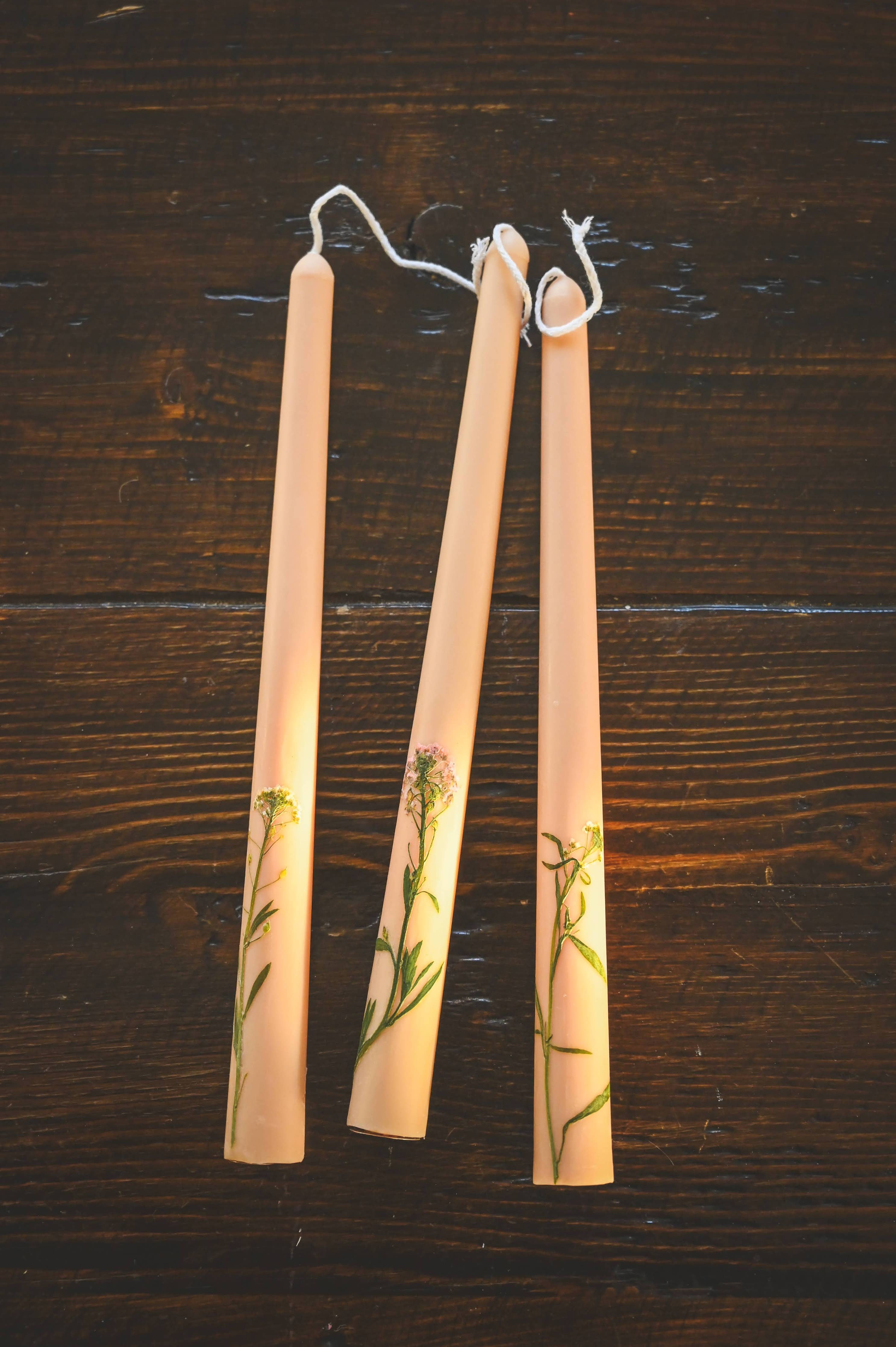 Three candles with floral designs on a wooden surface