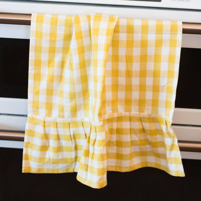 Yellow and white checkered towel hanging on a oven