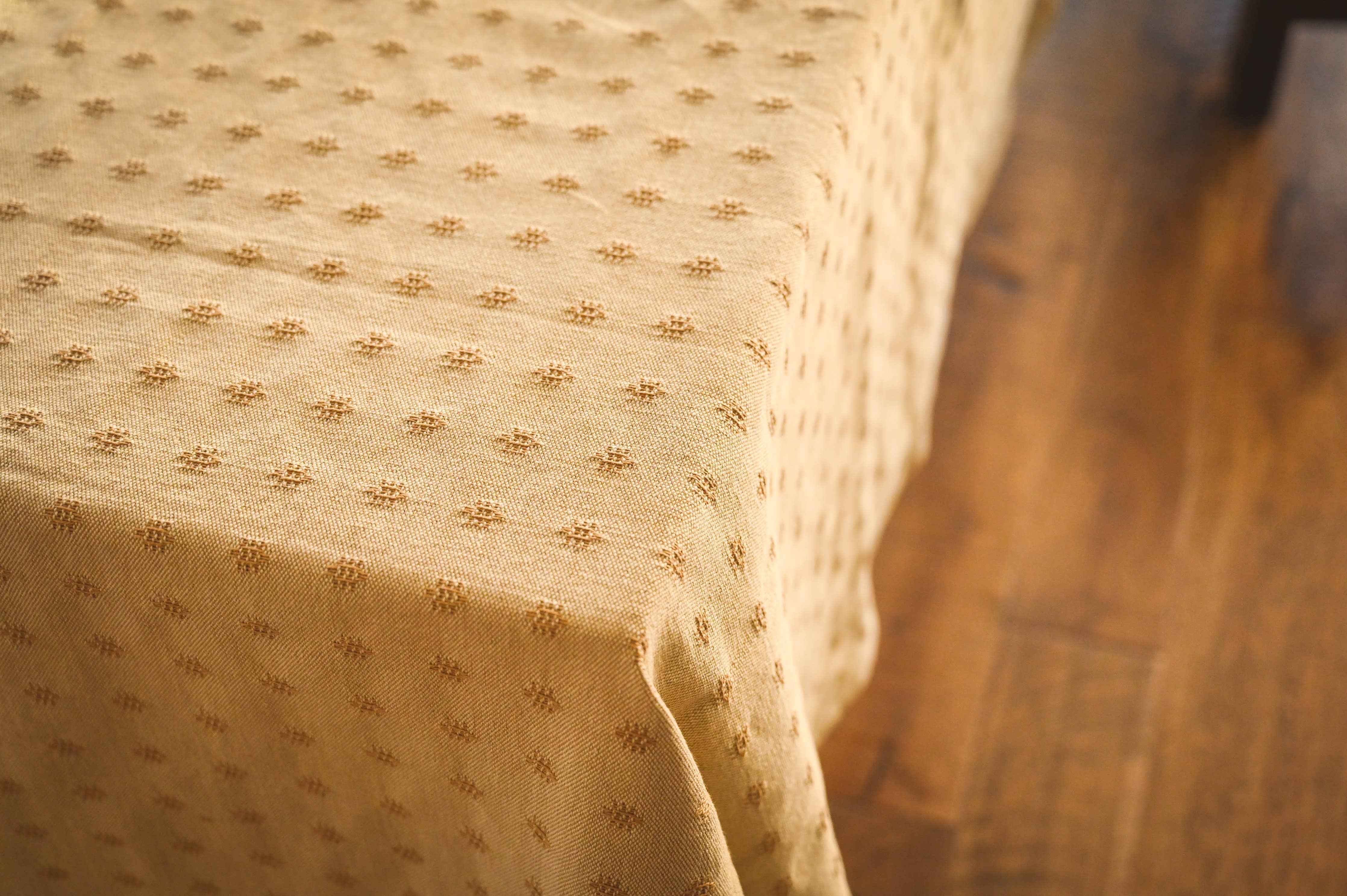Close-up of a tan tablecloth with a subtle pattern on a wooden surface.