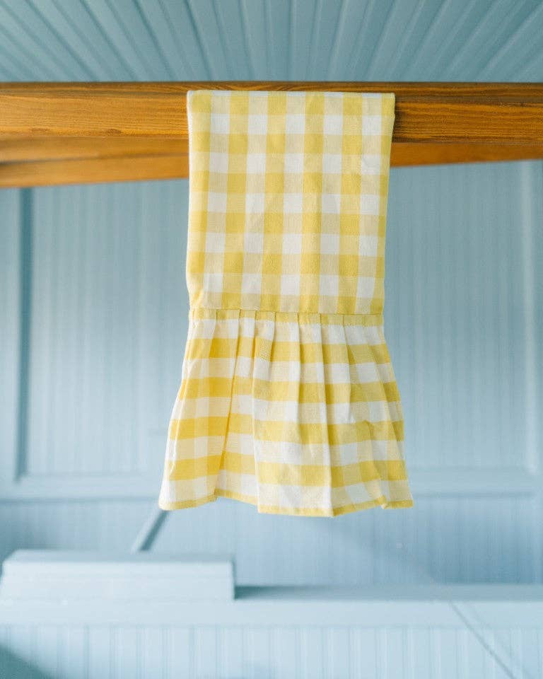 Yellow checkered towel hanging on a wooden rod against a light blue wall.