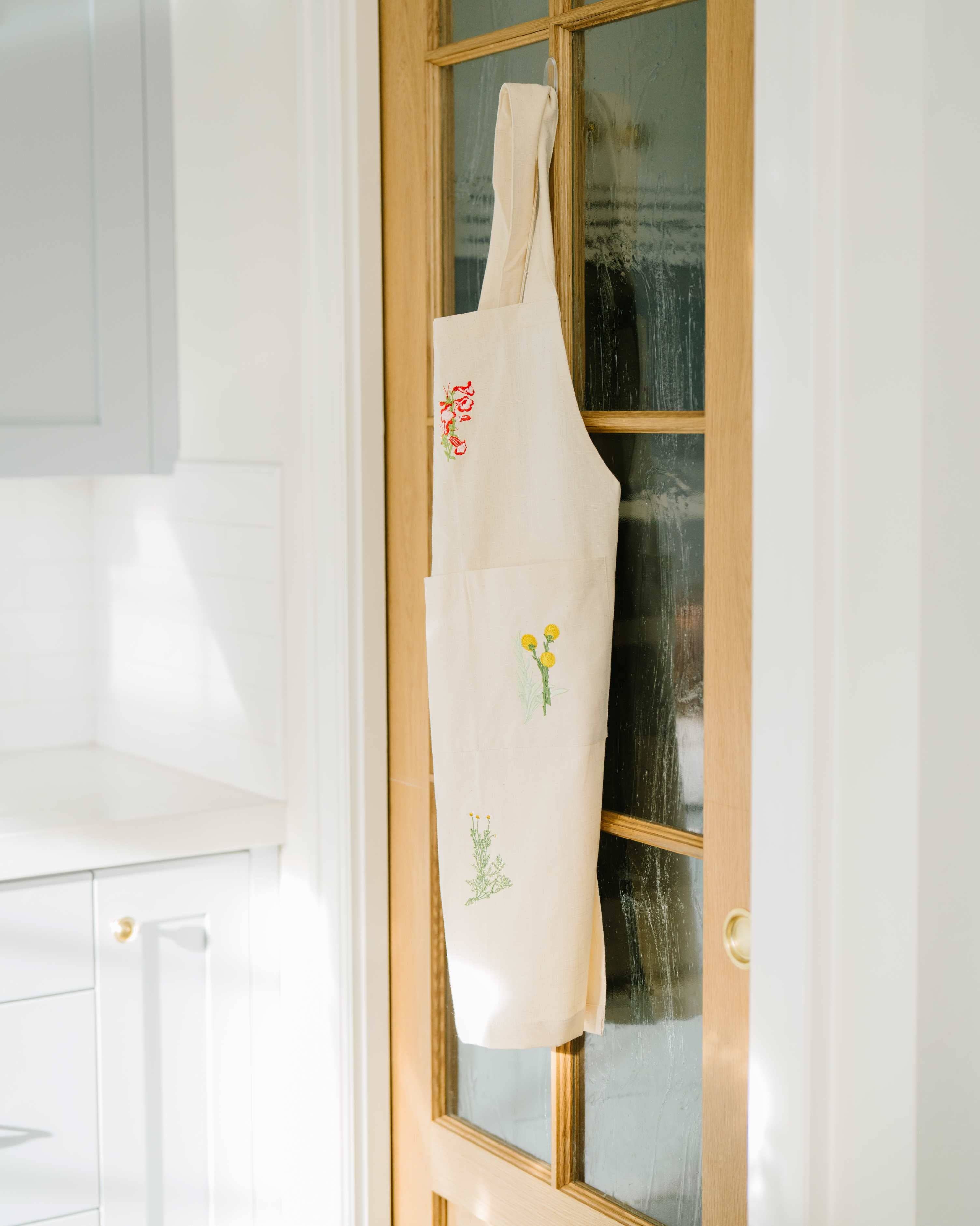 Close-up of embroidered botanical pockets on cotton apron