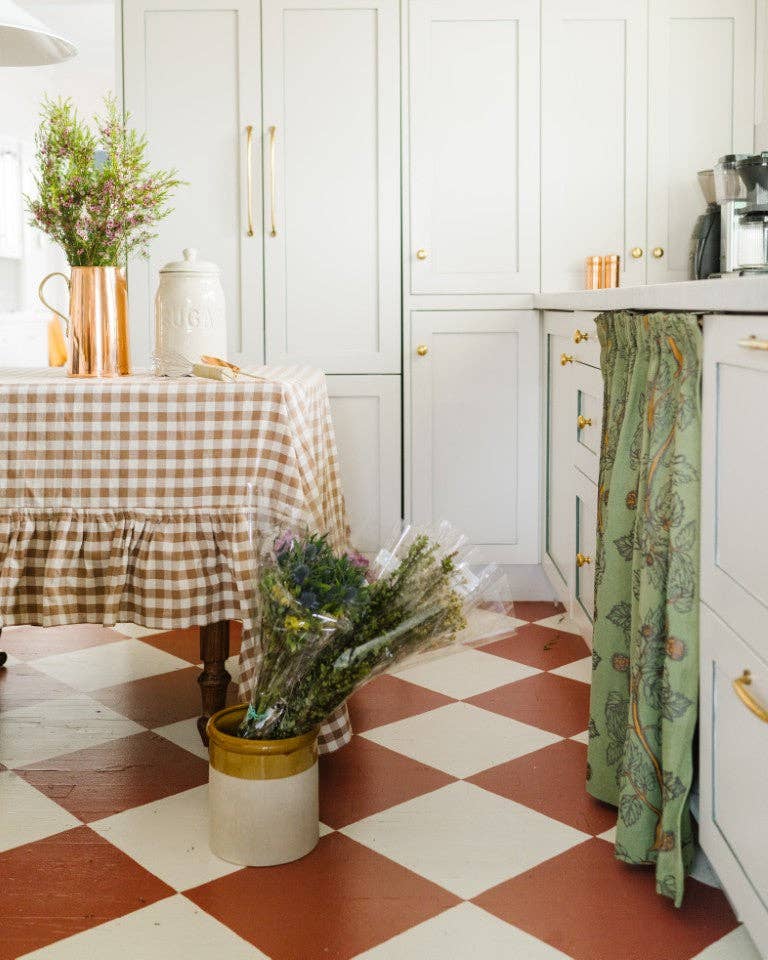 Kitchen interior with white cabinets, checkered floor, and decorative elements.