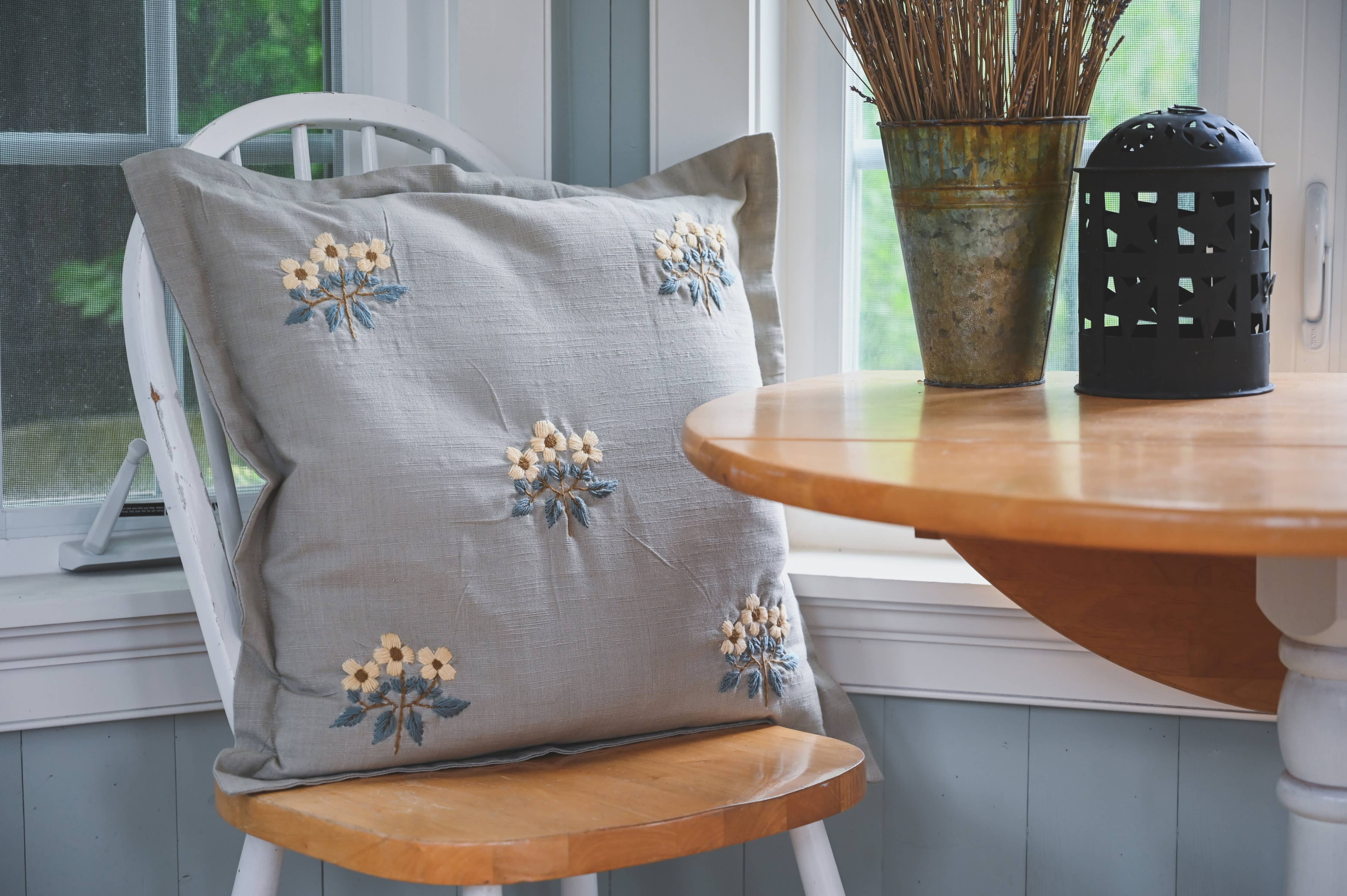 Vintage-inspired pillow with soft blue fabric and floral stitching
