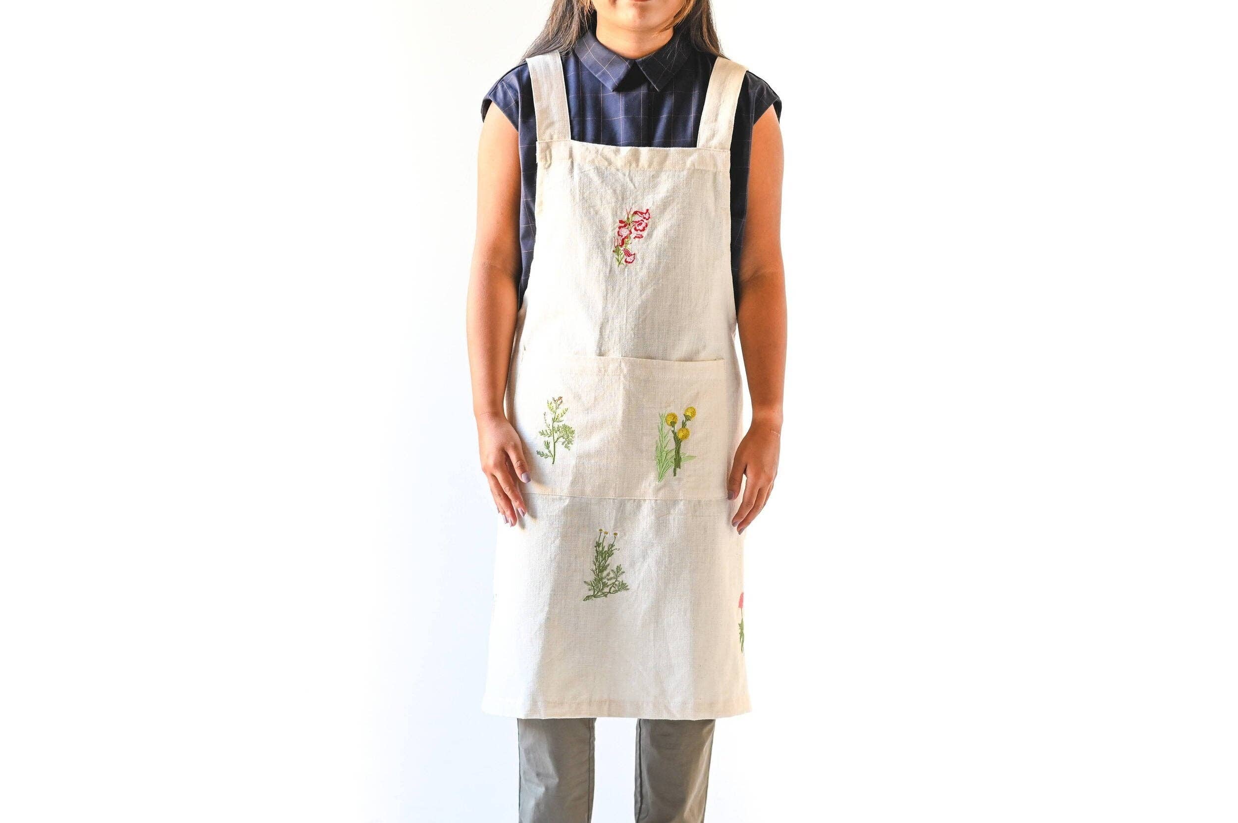 Person wearing a white apron with floral embroidery on a white background