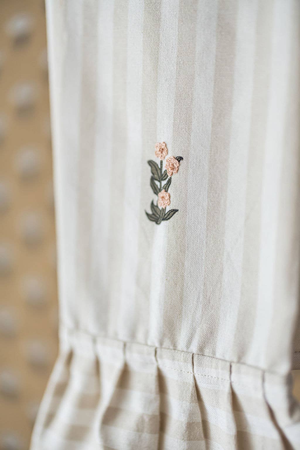 Neutral kitchen towel with soft stripes and feminine ruffle detail